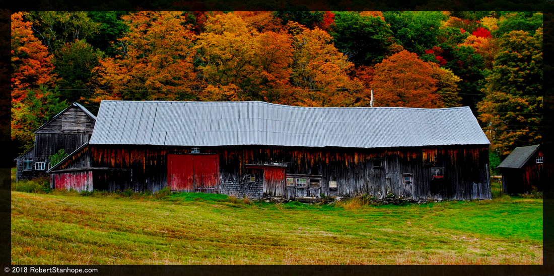 Rustic barn with vivid fall foliage backdrop.
